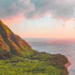 Breathtaking view of Kauai's lush greenery and ocean at sunset, with vibrant colors and dramatic landscapes.