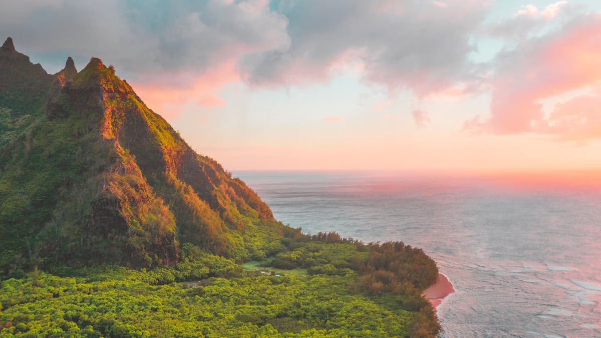 Breathtaking view of Kauai's lush greenery and ocean at sunset, with vibrant colors and dramatic landscapes.